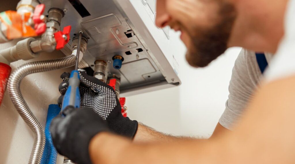 Workman connecting up new boiler with tools